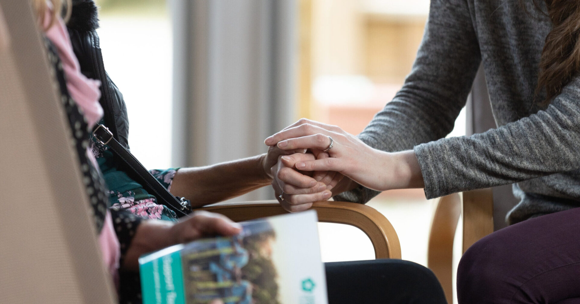 Heart of Kent Hospice care. A colleague holds the hand of a patient.