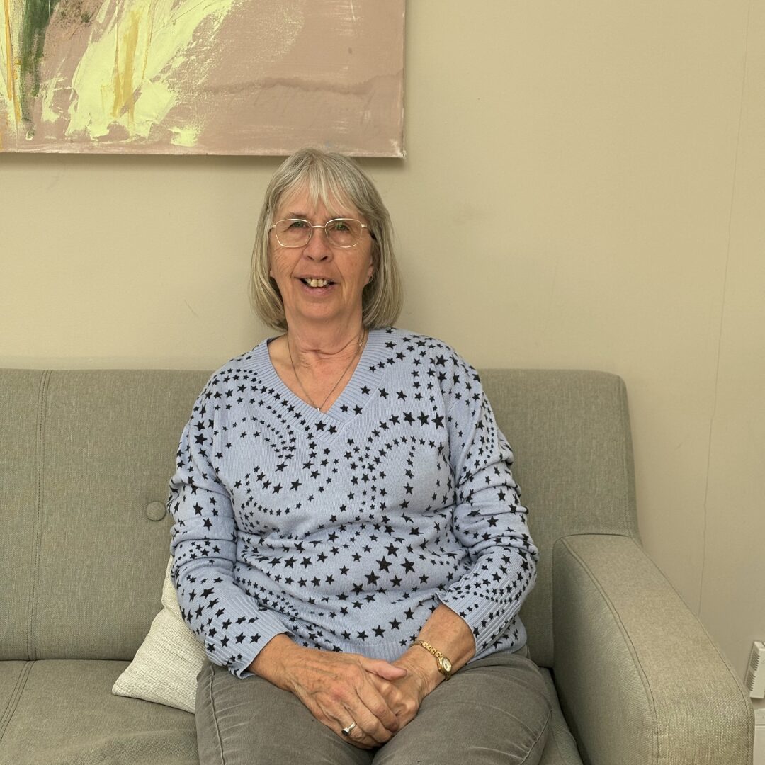 Light up a life – Maria A smiling woman sits on a sofa in the Hospice Hub