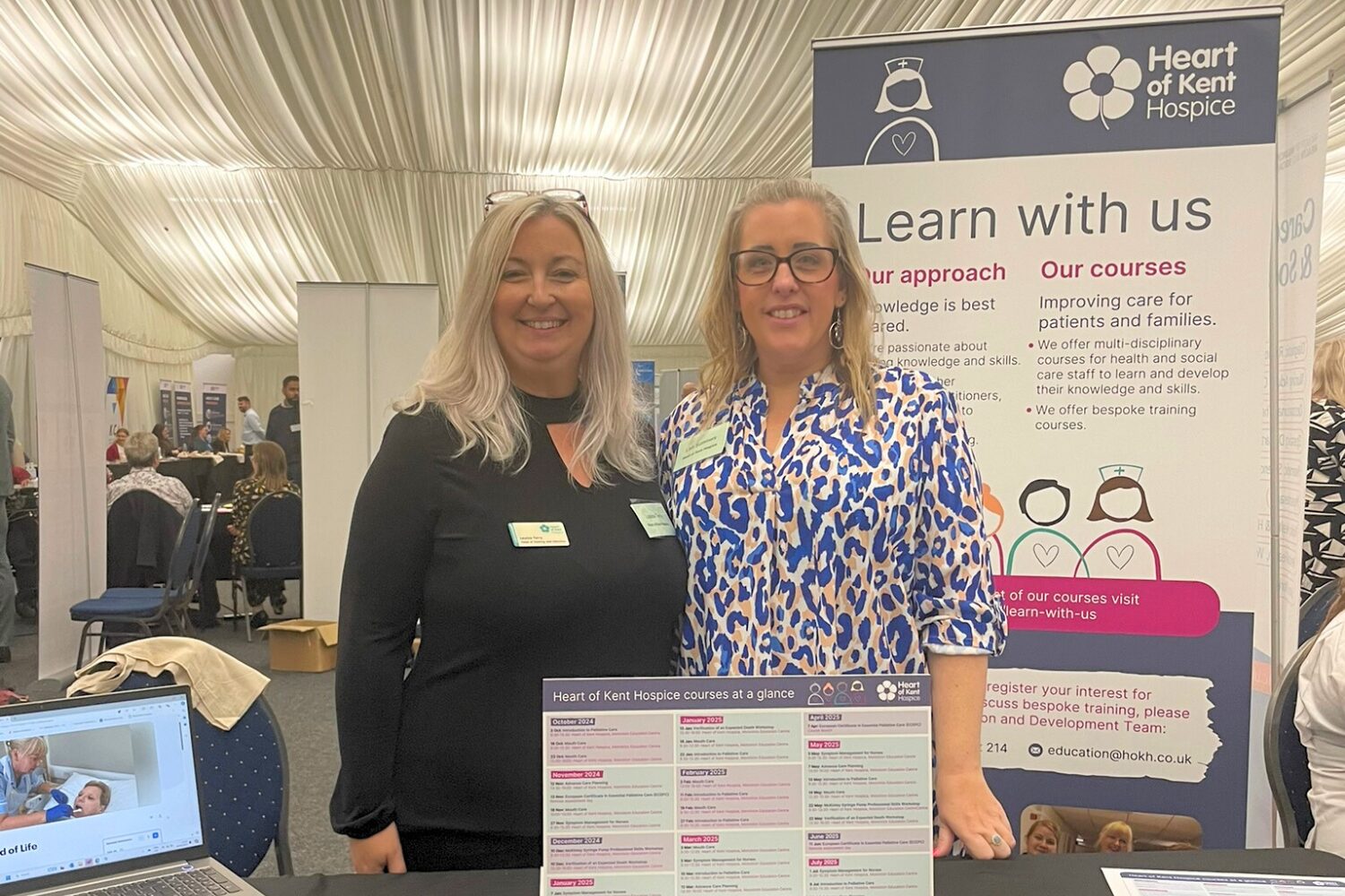 Learn with us Our team standing behind a table at an education/learning fair